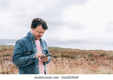 Man Traveller, Who Is Standing On Edge Of The Cliff On Irish Sea And Is Doing Photos On Smartphone. Amazing View During Staycation And Travelling In UK, Anglesey, South Stack Lighthouse