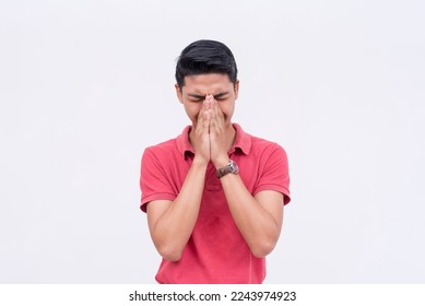 A man tries to contain his laughter, covering his face with his hands, but visibly struggling. Isolated on a white background.