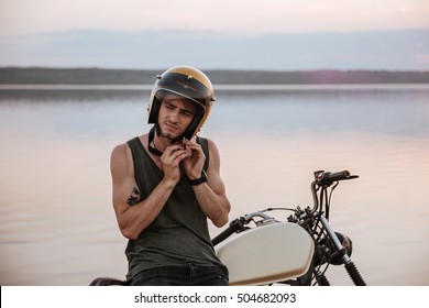 Man tries to put off his helmet while sitting on his motorcycle - Powered by Shutterstock