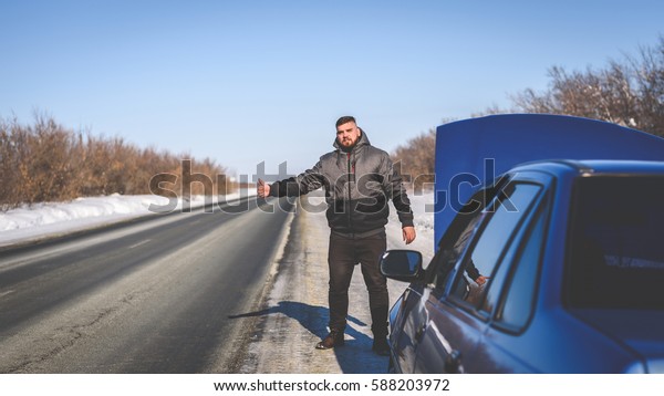 man tries to stop the car\
in winter