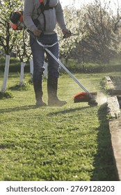 Man Trimming Grass With String Trimmer in Countryside Yard – Spring Work and Lifestyle Concept