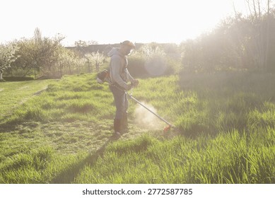 Man Trimming Grass With String Trimmer in Countryside Yard – Spring Work and Lifestyle Concept