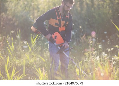 Man Trimming Weed With Weed Trimmer In Summer