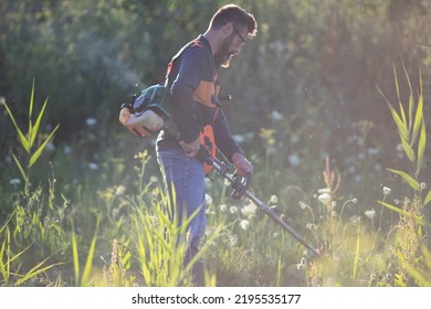 Man Trimming Weed With Weed Trimmer In Summer