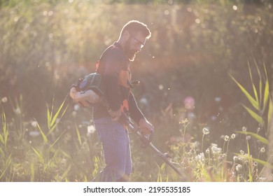 Man Trimming Weed With Weed Trimmer In Summer