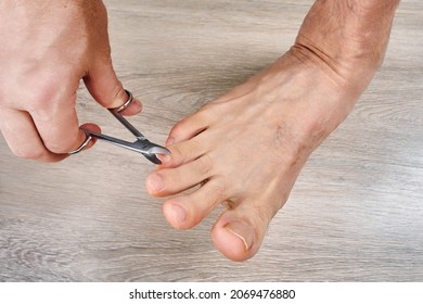 Man Trims His Toenails Using Toe Nail Scissors.