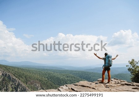 A man triumphantly threw his hands up standing on the top of the mountain, trekking alone in the canyon, mountain tourism in Europe, summer outdoor activities. High quality photo