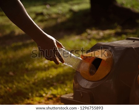 A man trowing plastic bottle into the cycle bin at the park