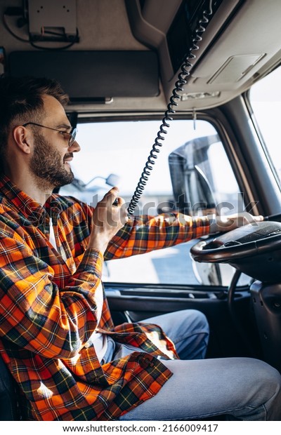 Man trucker driving in a cabin of his truck\
and talking on radio\
transmitter