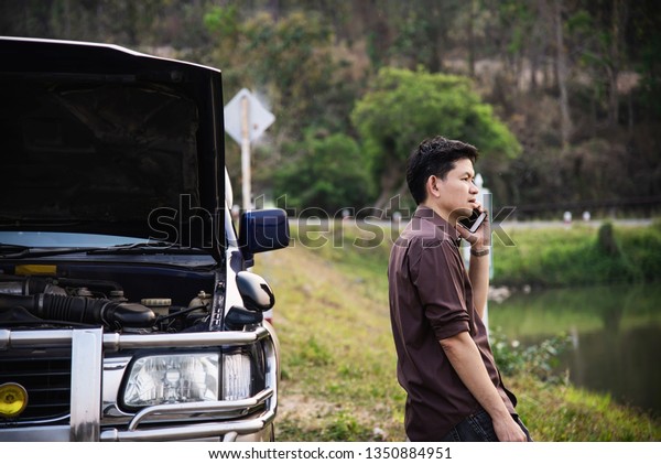 Man try\
to fix a car engine problem on a local road Chiang mai Thailand -\
people with car problem transportation concept\
