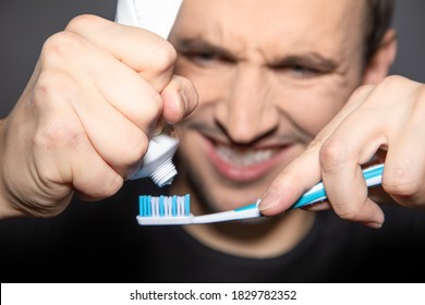 Man Try Hard To Squeeze Rest Out Of Empty Tube Of Toothpaste 