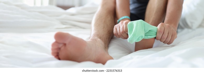 Man try to pull sock on foot, dress up to go out, sit on bed for comfort