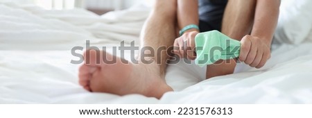 Man try to pull sock on foot, dress up to go out, sit on bed for comfort