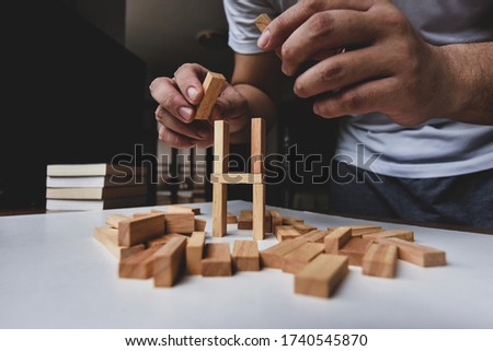 A man try to rebuild wooden blocks tower after them breakdown on white table  Stockfoto © 