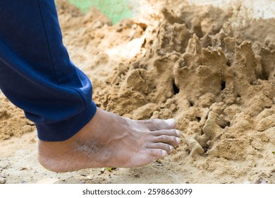 Hombre tratando de perturbar las colinas de hormigas con sus pies descalzos