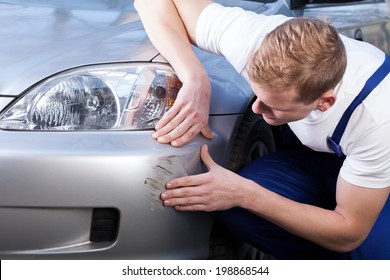 A Man Trying To Fix A Scratch On A Car Body