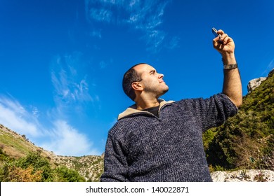 A Man Trying To Pick Up The Signal On His Mobile Phone