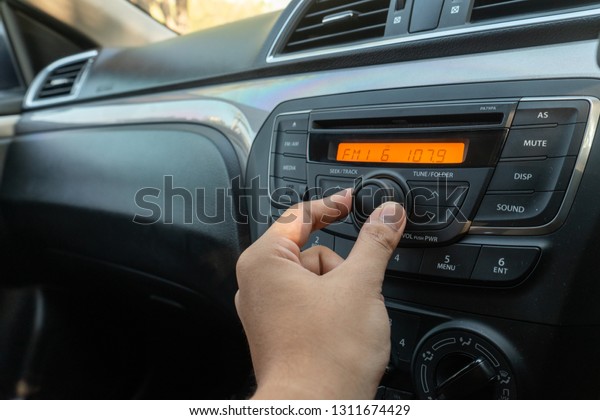 Man tuning button of car\
radio