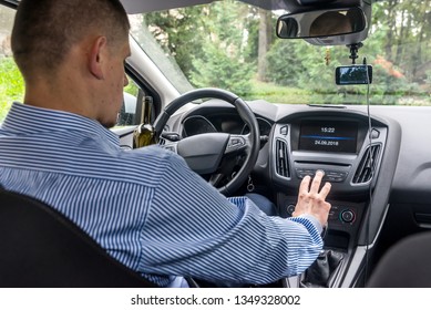 Man Tuning Radio In Car While Holding Alcohol Beverage