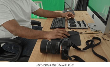 Man turning console knobs and using mouse with camera on wooden desk at computer workstation in studio; focus creativity.
