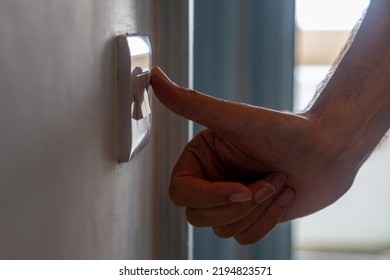 A Man Turning Off A Light Switch, With A Shallow Depth Of Field