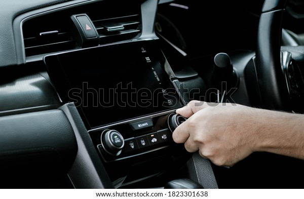 Man turning on car air conditioning system.\
Hand of man turning on car air conditioning system,Button on\
dashboard in car panel,Auto air\
conditioning.