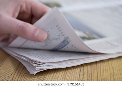 Man Turning A Page Of A Newspaper On A Wooden Table, Focus On Paper