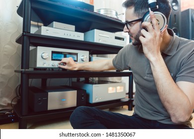 Man turning up the volume on home Hi-Fi stereo for louder music