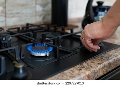 The man turns on the gas stove. Gas burner close-up. Gas stove in the kitchen in the house.