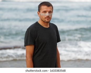 Man With Turquoise Sunblock At The Beach. Ocean Background. Surfer.