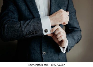 Man in a Tux fixing his Cufflink.