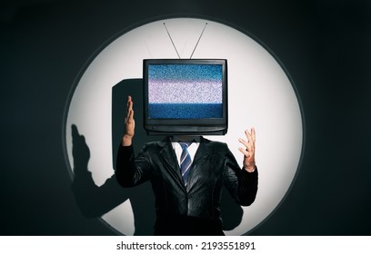 Man with TV instead of head. Media zombie concept with television addicted male in black coat with crossed arms posing on studio in the spotlight. Conceptual, contemporary art collage. Surrealism - Shutterstock ID 2193551891