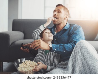 Man, tv remote and kid with popcorn by sofa for entertainment, snack and watching cartoon together. Family, father and son with feeding in living room for love, care and streaming of show at home - Powered by Shutterstock