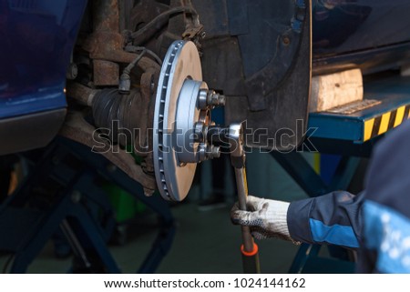 The man twists the screws on the disk, the machine. Disk brake repair in the car.