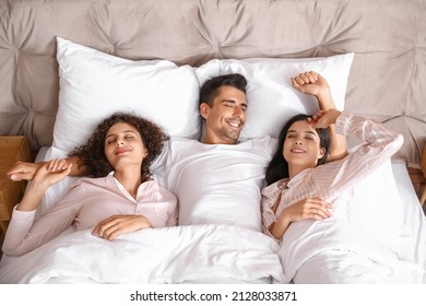 Man With Two Beautiful Women In Bed. Polyamory Concept