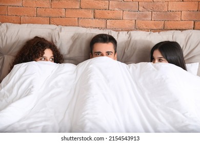 Man With Two Beautiful Women In Bed. Polyamory Concept