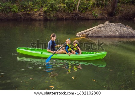 A man and two boys in a kayak on the river. Happy childhood