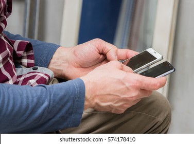 A Man With Two Phones In Hand, Checks And Makes A Choice