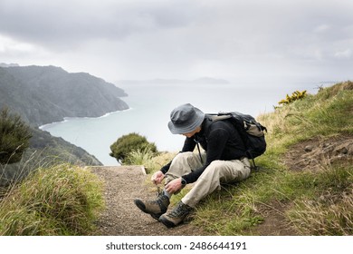 Man tying boot laces. Omanawanui track in the Waitakere Ranges. Auckland. - Powered by Shutterstock