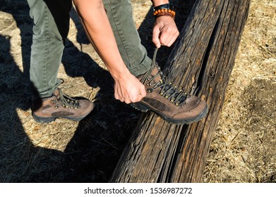 Man Tying Hiking Shoes On Wooden Log.