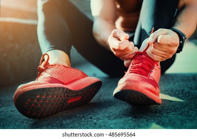 Man Tying Jogging Shoes.He Is Running Outdoors On A Sunny Day.