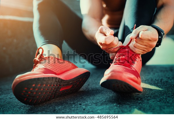 Man tying jogging shoes.He is running outdoors on a
sunny day.