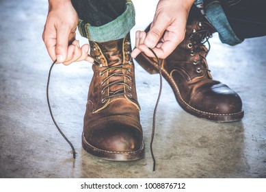 Man tying the laces on leather shoes boot.
