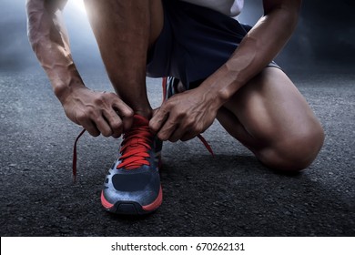 Man tying running shoes - Shutterstock ID 670262131