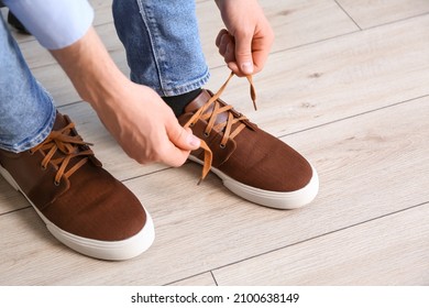 Man tying shoe laces at home, closeup