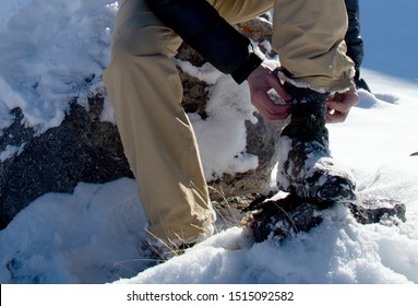 Man Tying Shoelaces On Hiking Boots In The Winter