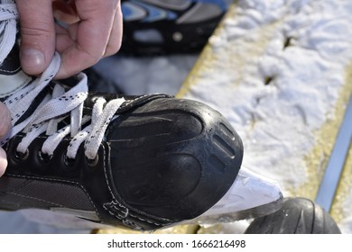 A Man Is Tying Shoelaces On Skates. Black Hockey Skates. Winter.