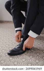 Man tying shoelaces while getting dressed for an event