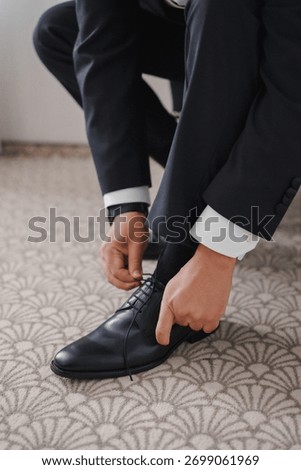 Man tying shoelaces while getting dressed for an event