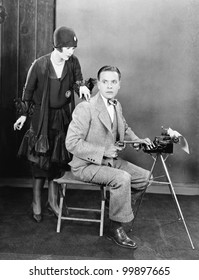 Man At A Typewriter Holding A Gun And A  Woman Tapping On His Shoulder